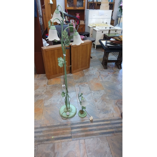 69 - Pair of floral-themed metal floor lamps with frosted glass shades. The lamp has leaf accents and a g... 