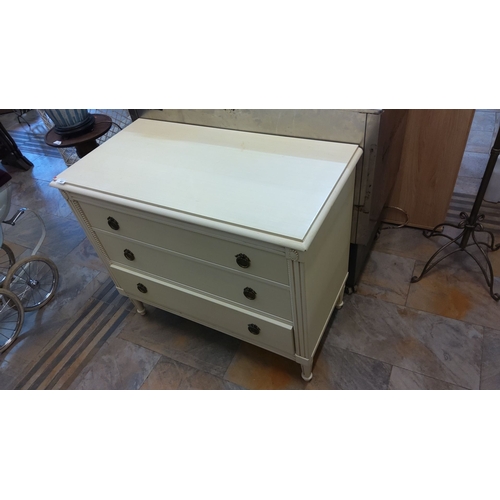 82 - Three-drawer chest, painted in cream. It has carved detailing and brass drawer pulls. It has a perio... 