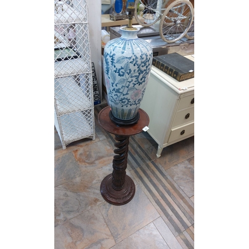 85 - Blue and white floral porcelain lamp base on a carved wooden pedestal stand.