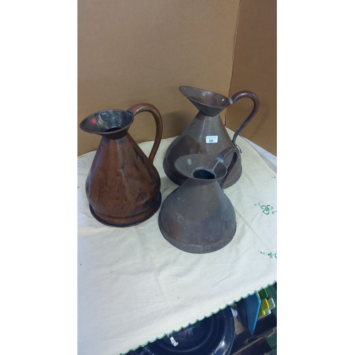 10 - Set of three vintage copper pitchers, with distinctive flared spouts and sturdy handles.