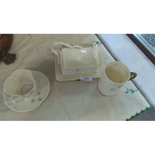 164 - Belleek porcelain set with a shamrock-decorated cup, saucer, mug, and thatched cottage butter dish. ... 