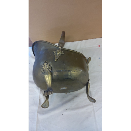 28 - Antique brass coal scuttle with ornate detailing and lion paw feet. Features a curved handle and sid... 