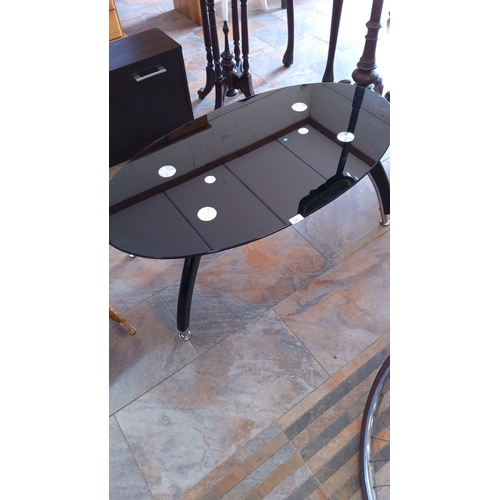 285 - Modern black glass coffee table with a sleek oval design. It features chrome accents and curved legs... 