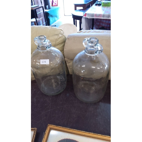 174 - Pair of vintage clear glass demijohn bottles with round bodies and narrow necks, featuring molded ha... 