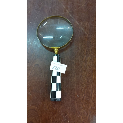 220 - Brass-rimmed magnifying glass with a black and white checkered handle. Classic design.