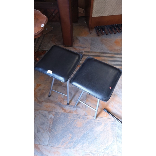 264 - Pair of black faux leather folding stools with metal frames.