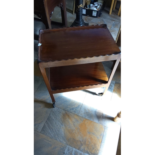 265 - Mahogany tea trolley on casters with two shelves and scalloped edges, from the mid-20th century.