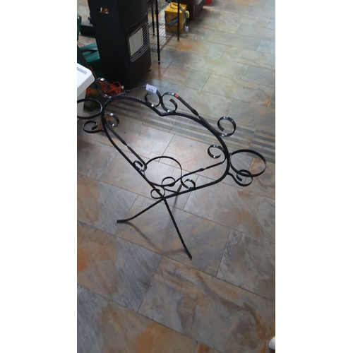 328 - Decorative black wrought iron plant stand with intricate scrollwork design.