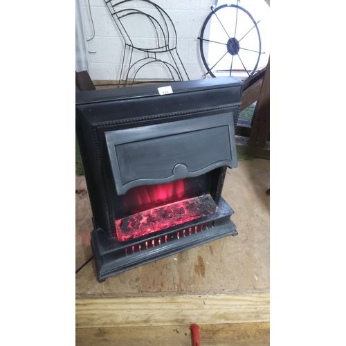 329 - Black cast iron-look finish electric fireplace heater with glowing ember effect.