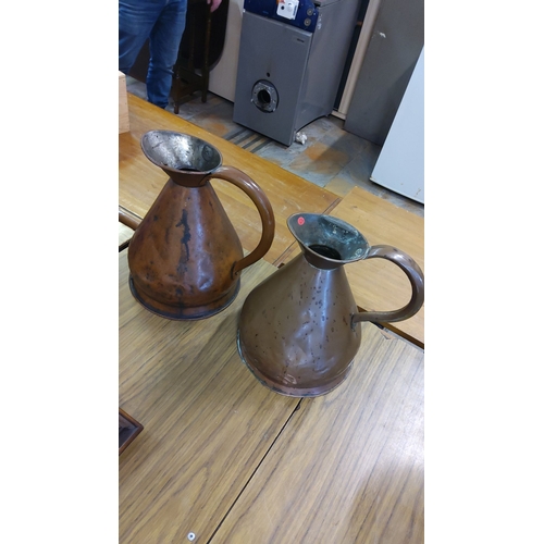 33 - Pair of large vintage copper-handled jugs with wide spouts and riveted seams, each featuring a patin... 