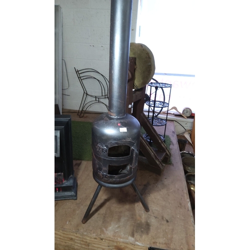 330 - Vintage metal wood-burning stove with chimney pipe. Features a cylindrical body on tripod legs.