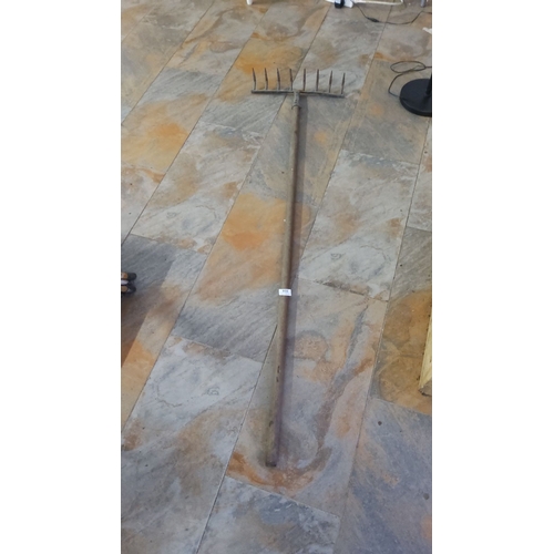 338 - Vintage iron garden rake with wooden handle featuring nine curved tines. Length: approximately 5 fee... 