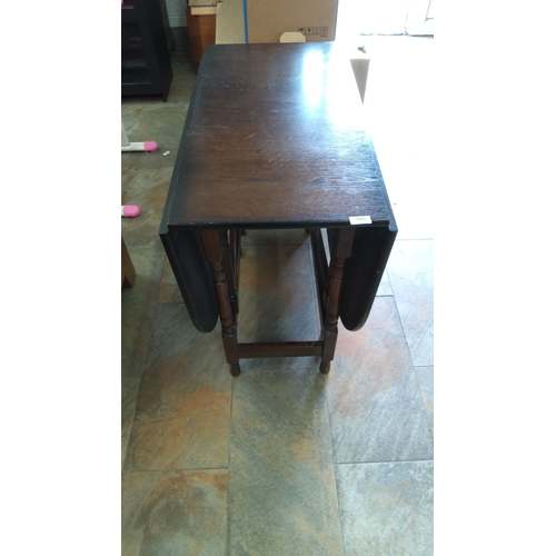 386 - Antique oak drop-leaf table with a dark finish, featuring turned legs and gateleg supports. From the... 