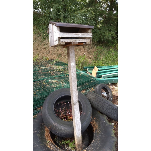 400 - Wooden birdhouse on a tall wooden post, slanted roof.