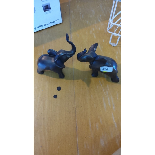 424 - Pair of black resin elephant figurines with their trunks raised.