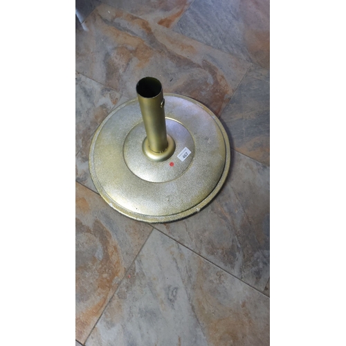 467 - Gold-colored metal parasol stand with textured surface, cylindrical center tube for support, and rou... 