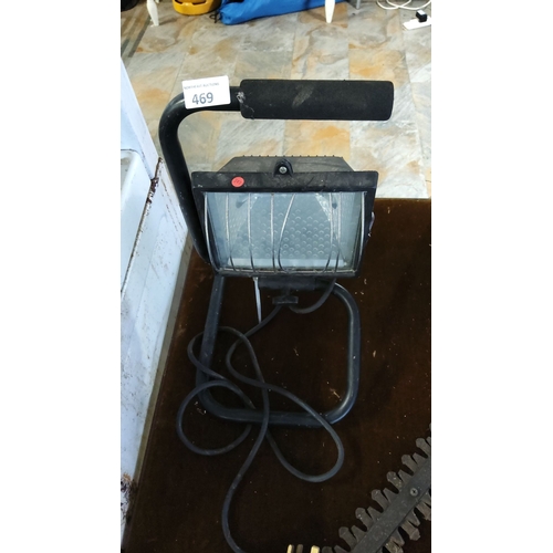 469 - Portable work light with adjustable stand. Features a metal cage for bulb protection and attached po... 