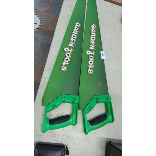 493 - Pair of handsaws with ergonomic green handles and green blades, labeled 