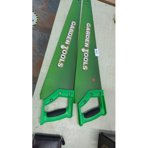 493 - Pair of handsaws with ergonomic green handles and green blades, labeled 