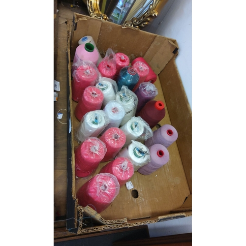 82 - 21 spools of yarn in various colors including pink, white, red, and purple, packaged in a cardboard ... 