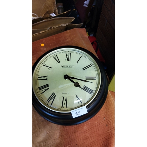 85 - Dunlevy quartz wall clock with Roman numerals and black frame. Diameter is 12 inches.