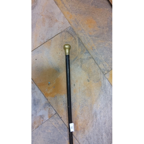 91 - Antique walking stick with a brass handle and black lacquered wooden shaft.