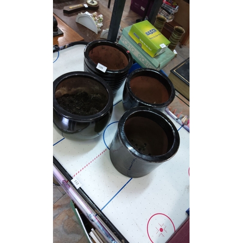 109 - Set of four black ceramic pots, varying in size, with a glazed finish.