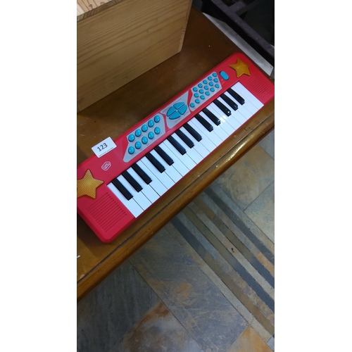 123 - Red electronic keyboard with yellow star accents, featuring black and white keys, blue buttons, and ... 