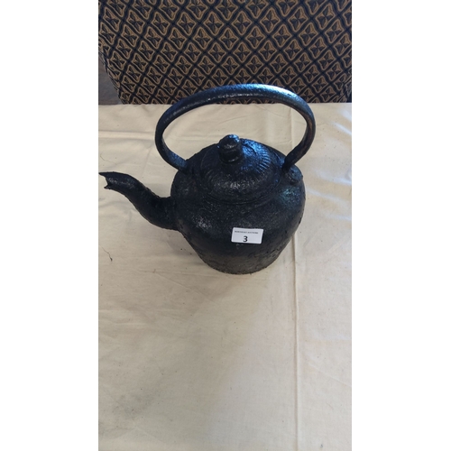 3 - Antique cast iron kettle with a textured handle and body, featuring a slightly curved spout and a fl... 