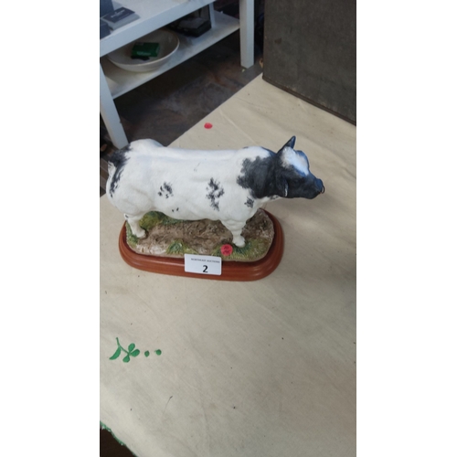 2 - Heavy Resin figurine of a black and white bull on a wooden base.