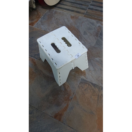 27 - White plastic folding step stool with handle cutouts.