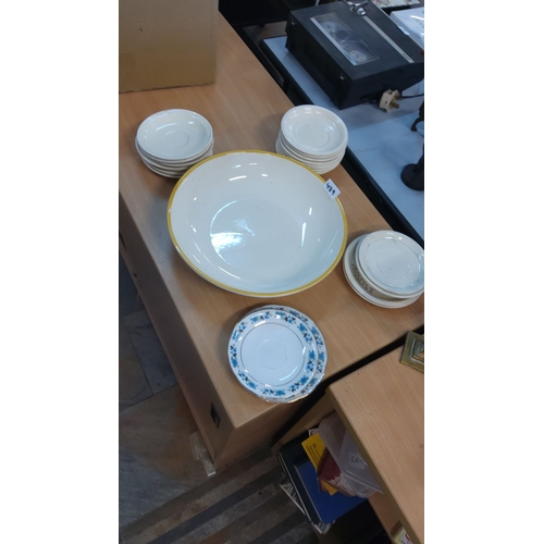 489 - Mixed lot of ceramic dishes, including white saucers, a large bowl with a yellow rim, and a floral p... 