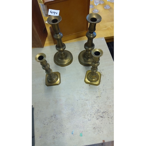 494 - A set of four vintage brass candlesticks features classic columnar designs with rounded and hexagona... 