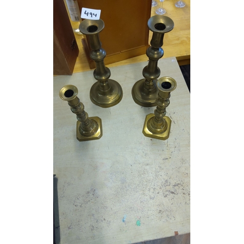 494 - A set of four vintage brass candlesticks features classic columnar designs with rounded and hexagona... 