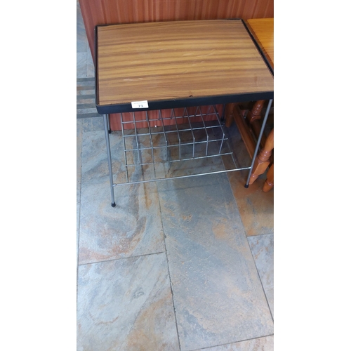 73 - Side table features a wood veneer top, metal legs, and a wire mesh magazine rack.