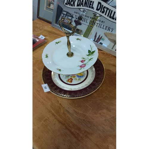 99 - Two-tier porcelain cake stand with floral and gold embellishments and ornate metal handle.