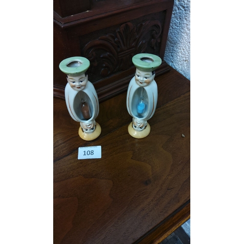108 - Pair of ceramic hourglasses with dual-faced characters, featuring green hat tops and smiling visages... 