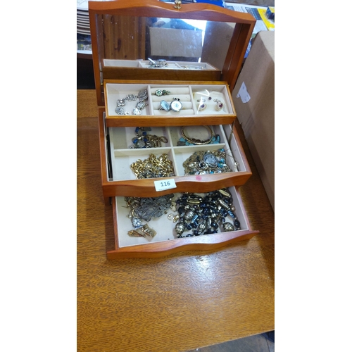 116 - Wooden box containing assorted jewelry items such as rings, bracelets, and necklaces. Features mixed... 