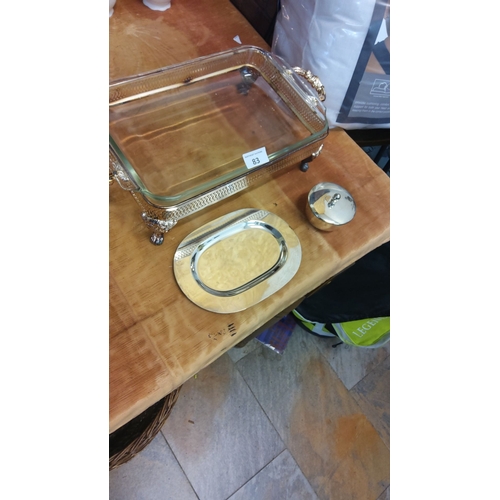 83 - Silver serving set featuring a glass tray with ornate handles, oval platter, and lidded dish.