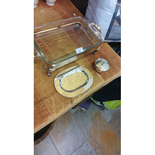 83 - Silver serving set featuring a glass tray with ornate handles, oval platter, and lidded dish.