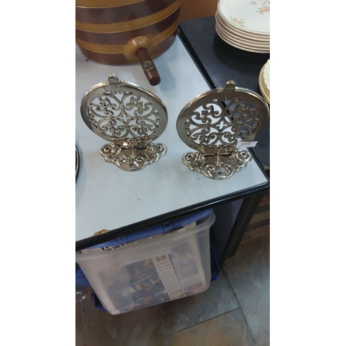 217 - Pair of vintage chrome trivet stands with intricate scrollwork, reflecting a Victorian design influe... 