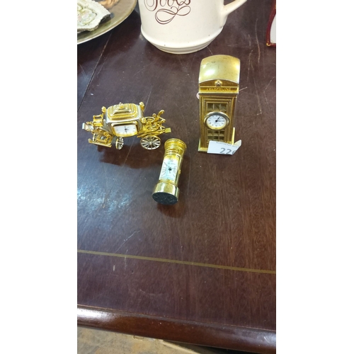 226 - Three miniature carriage clocks in gold-tone metal, featuring ornate designs. Includes a carriage, p... 