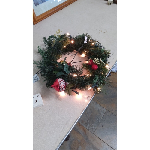 28 - Festive wreath adorned with LED lights, pine cones, and red ornaments.