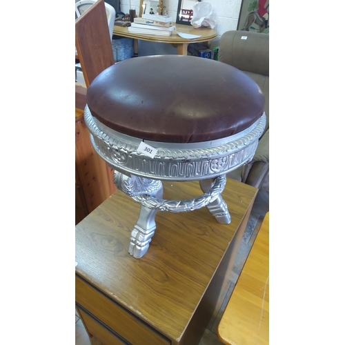 301 - Silver-painted stool with ornate carvings and a brown leather seat cushion. Includes intricately des... 