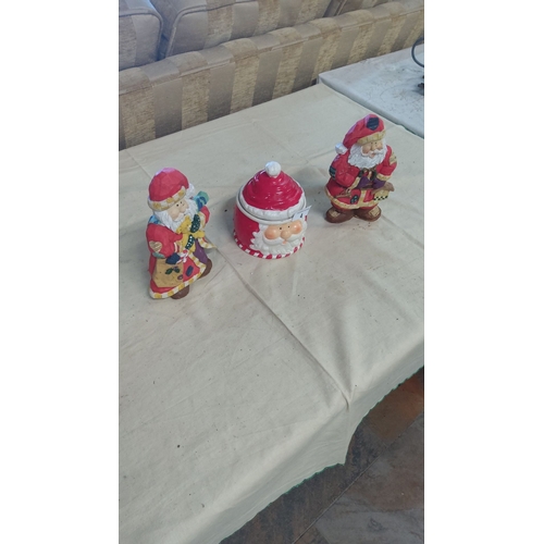 4 - Set of three ceramic Santa Claus figurines, featuring colorful holiday designs and a Santa face cook... 