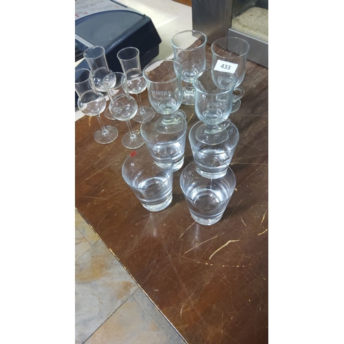 433 - Set of branded assorted drinking glasses, including branded Powers Gold Label glasses.