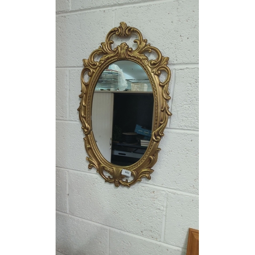 441 - Ornate oval mirror with a gold-toned frame, featuring intricate scrollwork and floral motifs. Victor... 