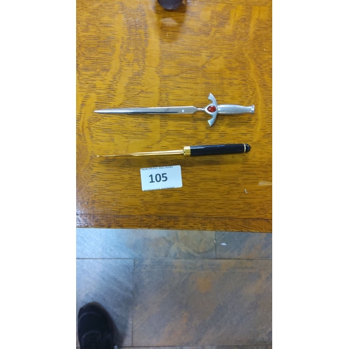 105 - Two vintage letter openers: one features a sword design with a red gemstone; the other is black with... 