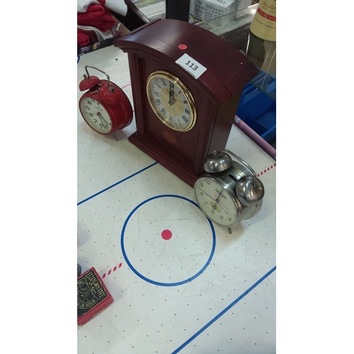 113 - Set of three vintage clocks: wooden mantel clock with Roman numerals, red twin-bell alarm clock, and... 