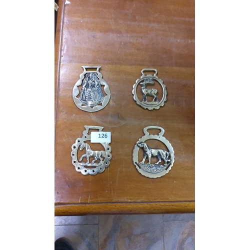 126 - Set of four brass horse brasses featuring traditional and animal designs.